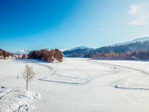 Der Reintalersee in Kramsach, eingebettet in Schnee, auf dem See Spuren für Fußgänger und Eisläufer  | © Alpbachtal Tourismus | Matthias Sedlak 