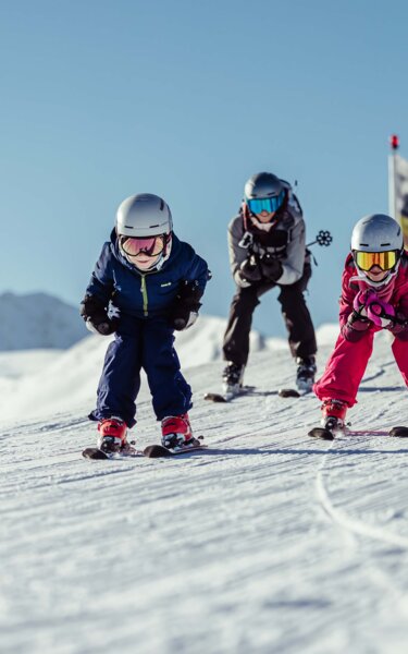 Eine Familie, bestehen aus Mutter, Vater, Tochter und Sohn, fahren gemeinsam, im Schuss, die Piste runter  | © Alpbachtal Tourismus | shootandstyle 