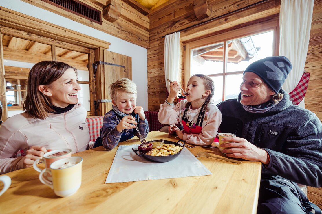 Eine Familie isst auf der Skihütte das typische Tiroler Gericht, Kaiserschmarrn | © Alpbachtal Tourismus | shootandstyle 