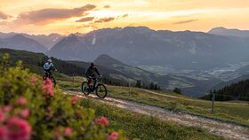 Ein Paar fährt mit dem Rad, bei Sonnenuntergang in Richtung Kolber in Reith. | © Alpbachtal Tourismus | shootandstyle