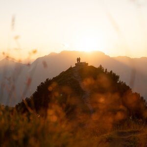 Zwei Personen stehen neben der Rastbank Gratlspitze, sie genießen den wundervollen Sonnenuntergang  | © Alpbachtal Tourismus  | Torsten Mühlbacher 