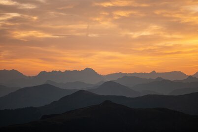Auf diesem Bild sieht man den wunderschönen Sonnenuntergang am Wiedersberger Horn, er erstrahlt in Gelb- und Orangetönen  | © Alpbachtal Tourismus | shootandstyle 