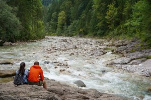 Auf diesem Bild zu sehen ist die Brandenberger Ache, rundherum die blühende Natur, am Bachufer sitzen eine Frau und ein Mann  | © Alpbachtal Tourismus 