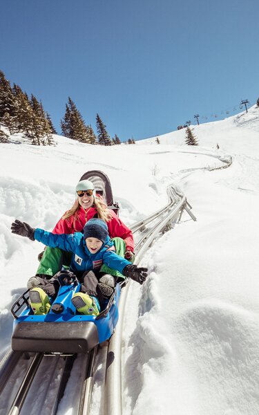 Auf diesem Bild zu sehen ist eine Mutter mit ihrem Sohn, während der Fahrt mit dem Alpin Coaster Lauser Sauser in Alpbach  | © Ski Juwel Alpbachtal Wildschönau | shootandstyle 