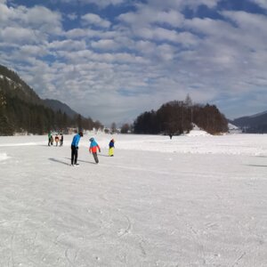 Auf diesem Bild zu sehen sind einige Menschen, welche gerade auf dem eingefrorenen Reintalersee eislaufen | © Alpbachtal Tourismus 