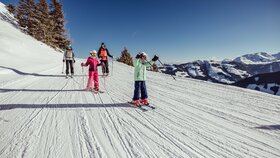 Eine Familie fährt gemeinsam der Skipiste in Alpbach entlang, die Kinder fahren vor, die Eltern hinten nach  | © Alpbachtal Tourismus | shootandstyle 