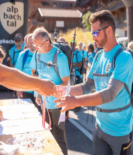Auf diesem Bild zu sehen sind einige Teilnehmer der 24h Wanderung, sie sind am Ziel angekommen und holen sich ihre Urkunden sowie ihre Medaillen ab | © Alpbachtal Tourismus | shootandstyle 