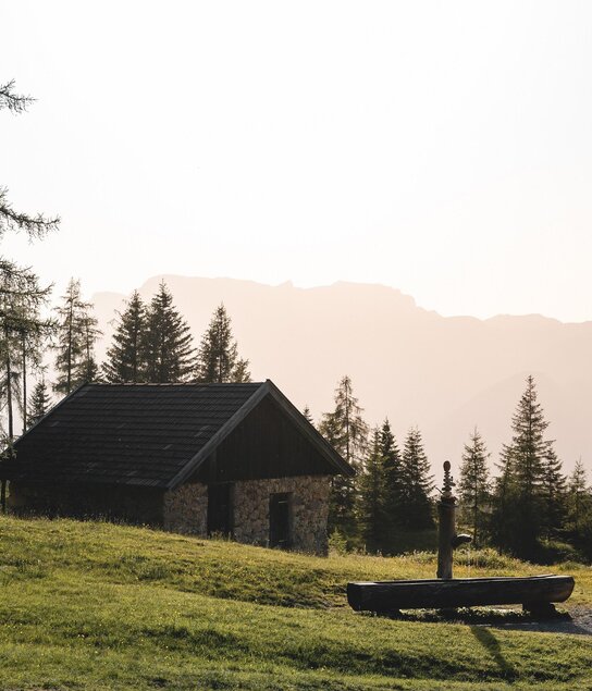 Wanderer mit Brunnen und Hütte Holzalm Brixlegg So